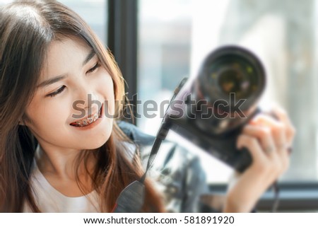 Young woman using Professional Camera and smiling in coffee shop.