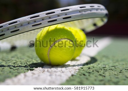 Tennis balls and racket on a green tennis hard court