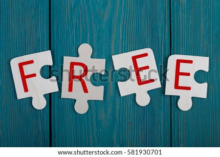Business Concept - Jigsaw Puzzle Pieces with text "FREE" on blue wooden background