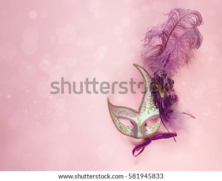 Festive Carnival Background with masks with feathers and copy space. Carnival mask on a pink background. 