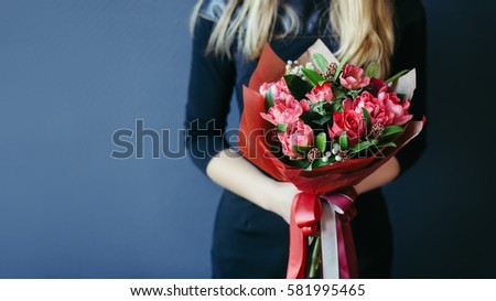 Bouquet of red tulips in girs hands. Unrecognisable.