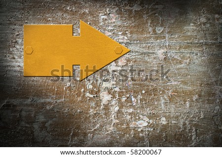 Metallic gold sign of pointer on an old concrete wall