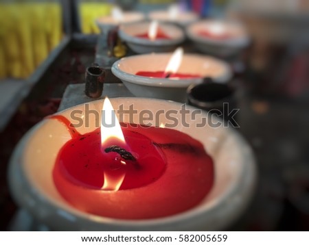 Red candle in ceramic bowl is lighting to respect buddha at Thai temple