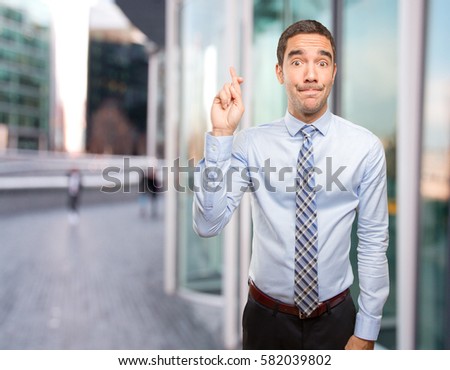 Hopeful businessman finger cross gesture