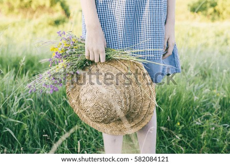 Straw hat and wildflower bouquet on the hands of little girl