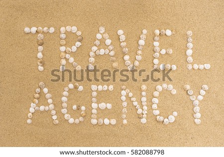 Travel Agency written with seashells on a sandy beach.