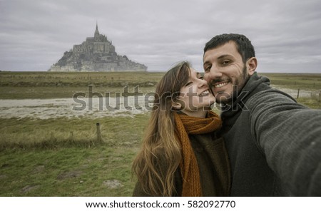 beautiful couple taking a selfie in front of Mont Saint Michel. France