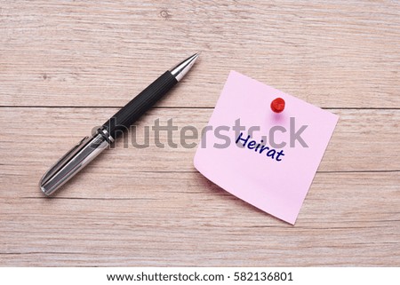 German word "Heirat" as concept on pink sticky note and wooden board