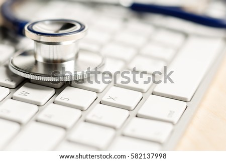 Stethoscope head lying on silver keyboard closeup. Medical concept. Modern medicine and high tech equipment concept