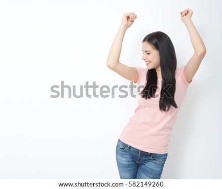 Portrait of a happy young woman dancing on gray background