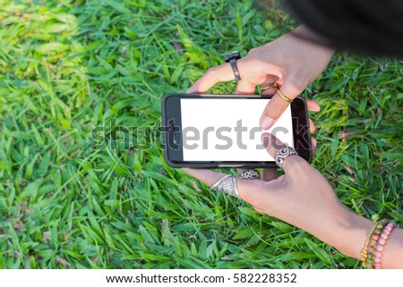 Woman using smart phone on ground grasses background