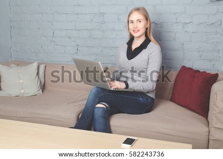 young woman sitting on the couch with a laptop