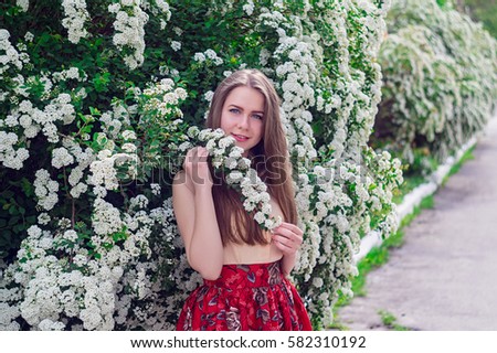 Portrait of a beautiful brunette with long hair. to bloom on trees. dressed in red underwear in a floral pattern and a yellow blouse. Springtime.