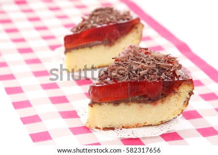 served two slices of delicious cherry cheese cake with cherry topping and decorated with chocolate on checkered tablecloth
