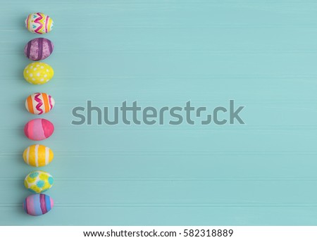 Colorful Easter Eggs in a line on side of a Teal Blue Beadboard Wood Background with extra, blank room or space for copy, text, or your words.  It's horizontal and perfect for a card or party invite