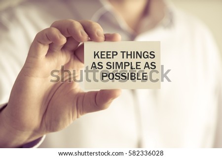 Closeup on businessman holding a card with text KEEP THINGS AS SIMPLE AS POSSIBLE, business concept image with soft focus background and vintage tone