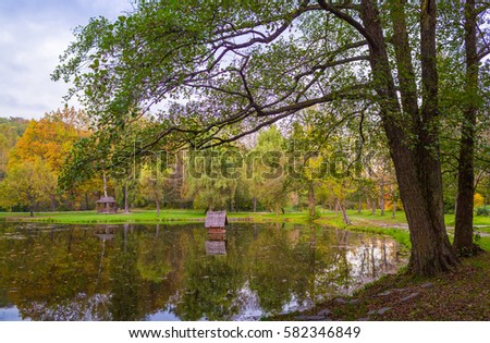 Autumn park with pond and wooden alcoves