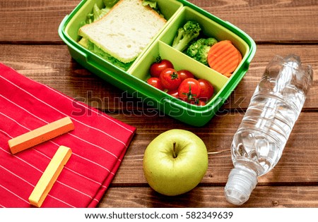 lunch box for kid with fresh vegetables on wooden background