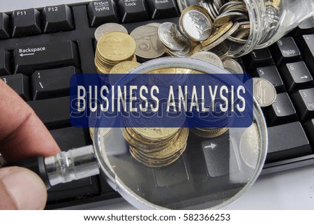 Magnify glass and coins on keyboard. Business analysis concept with conceptual words