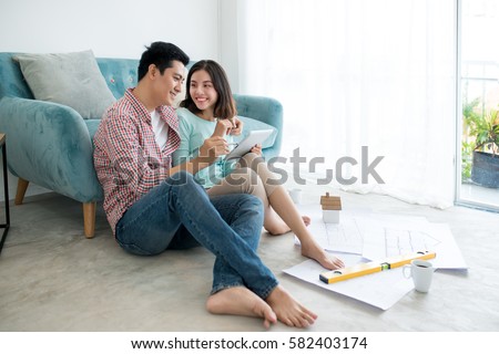 Attractive young asian adult couple planning new home design. Royalty-Free Stock Photo #582403174