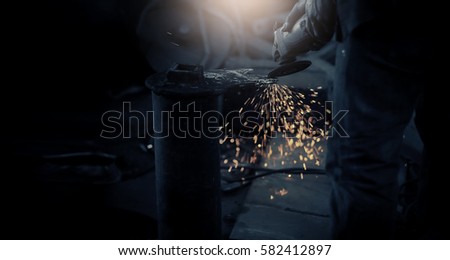 Local worker grinding,sparks during working with grinder in the old factory.Real situation picture and color toned.