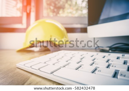 Safety work in Industrial and Factory concept. Engineer Construction Safety hat helmet on office working desk with desktop computer. Royalty-Free Stock Photo #582432478