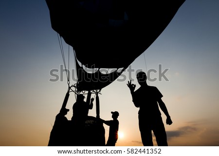 Silhouette of people with hot air balloon in the background at sunset, backlit by sunlight photography