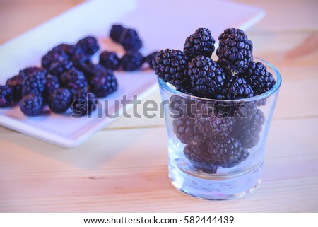 Close up fresh blackberry in glass bowl on wooden table / Selective focus