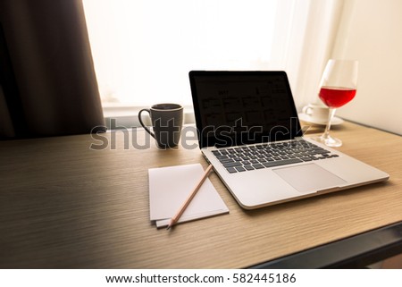 Computer laptop, wine, coffee of freelancer are on wooden table, working at home, home office