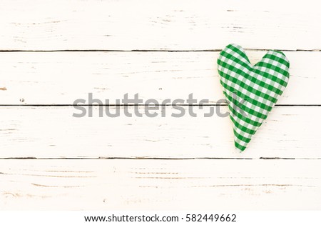 Green heart on white wood background with copy space.