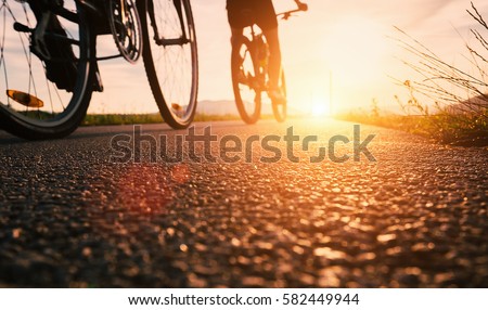 Bike wheels close up image on asphalt sunset road Royalty-Free Stock Photo #582449944
