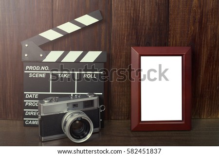 Old camera with empty photo frame on wood background (color vintage tone)