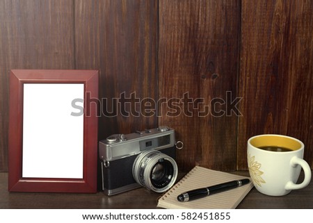 Old camera with empty photo frame and coffee on wood background (color vintage tone)
