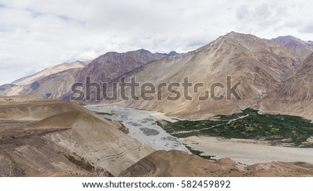 Human settlement along a river in barren mountainous terrain of Ladakh, India, Asia.