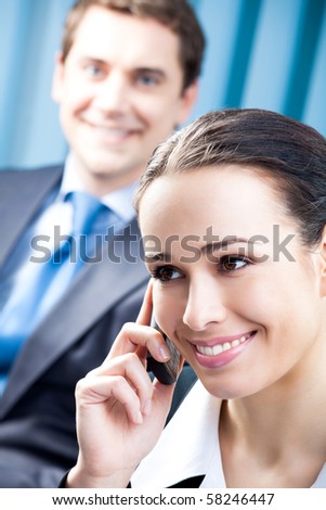 Successful businesswoman with cellphone and colleague, at office