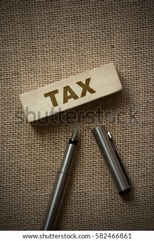 TAX on wooden block on a brown background