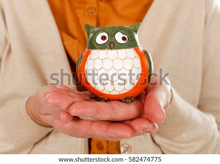 Close up picture of an elderly woman holding an owl as the symbol of wisdom
