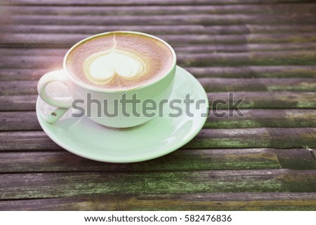 a selective focus picture of a cup of coffee on wooden table 