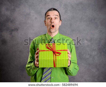 young  man in green shirt and necktie with green gift box is surprised