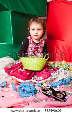 Beautiful 3 year old girl dressed in dirndl playing with confetti in the studio.
