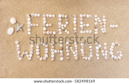 German text Ferienwohnung means vacation rental or holiday flat written from seashells on a sand beach.