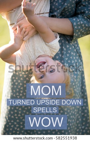Young mom and cheerful adorable blond girl playing, having fun together in park in summertime, mother playfully with little daughter. Photo with motivational text "Mom turned upside down spells wow" 