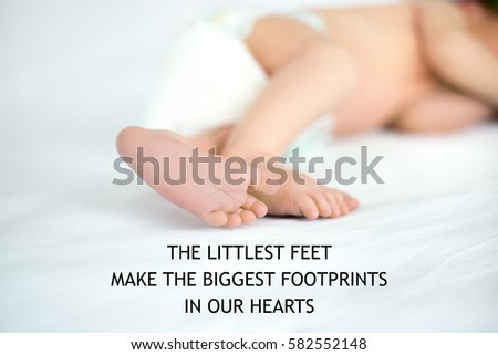 Close up of tiny sweet feet of sleeping newborn kid lying on white bed. Concept image. Photo with motivational text "The littlest feet make the biggest footprints in our hearts". Square image 