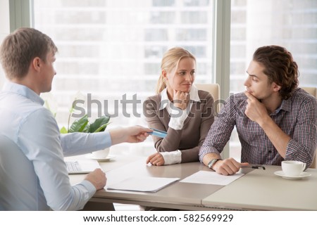Bank consultant trying to convince clients to get a loan, offering credit card with high interest rate. Middle-class family sorting out finances and budget, not sure in the choice, looking doubtful  Royalty-Free Stock Photo #582569929