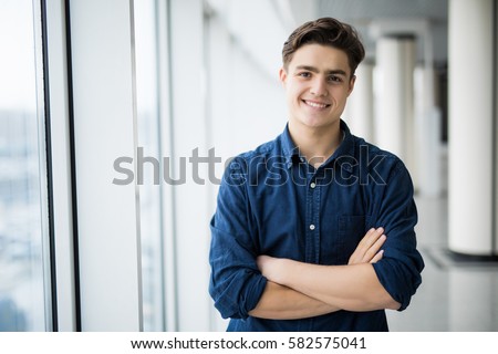 Portrait of young man with crossed hands near in window. Royalty-Free Stock Photo #582575041