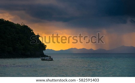 Raining Cloudy sky over the sea as rain falls near island with boat in front