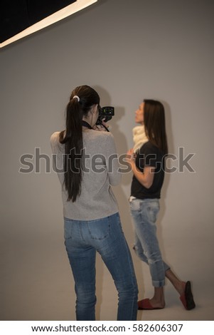 Photographer woman working with model young girl  in photo studio with equipments.  under soft boxes light. 