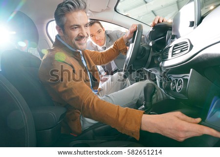 Man sitting inside vehicle in car dealership