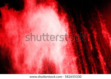 Abstract red dust explosion on  black background. Abstract red powder splatted on black background. Freeze motion of red powder exploding.