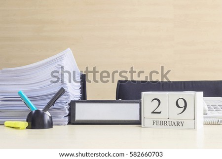 Closeup white wooden calendar with black 29 february word on blurred brown wood desk and wood wall textured background in office room view with copy space in selective focus at the calendar